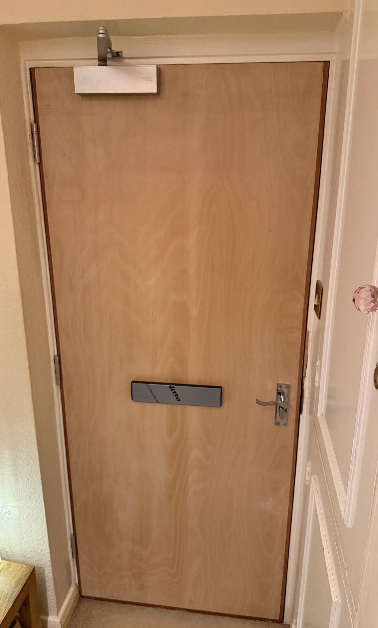Timber fire doorset with closer, hinges, handle and letter plate, photographed during installation