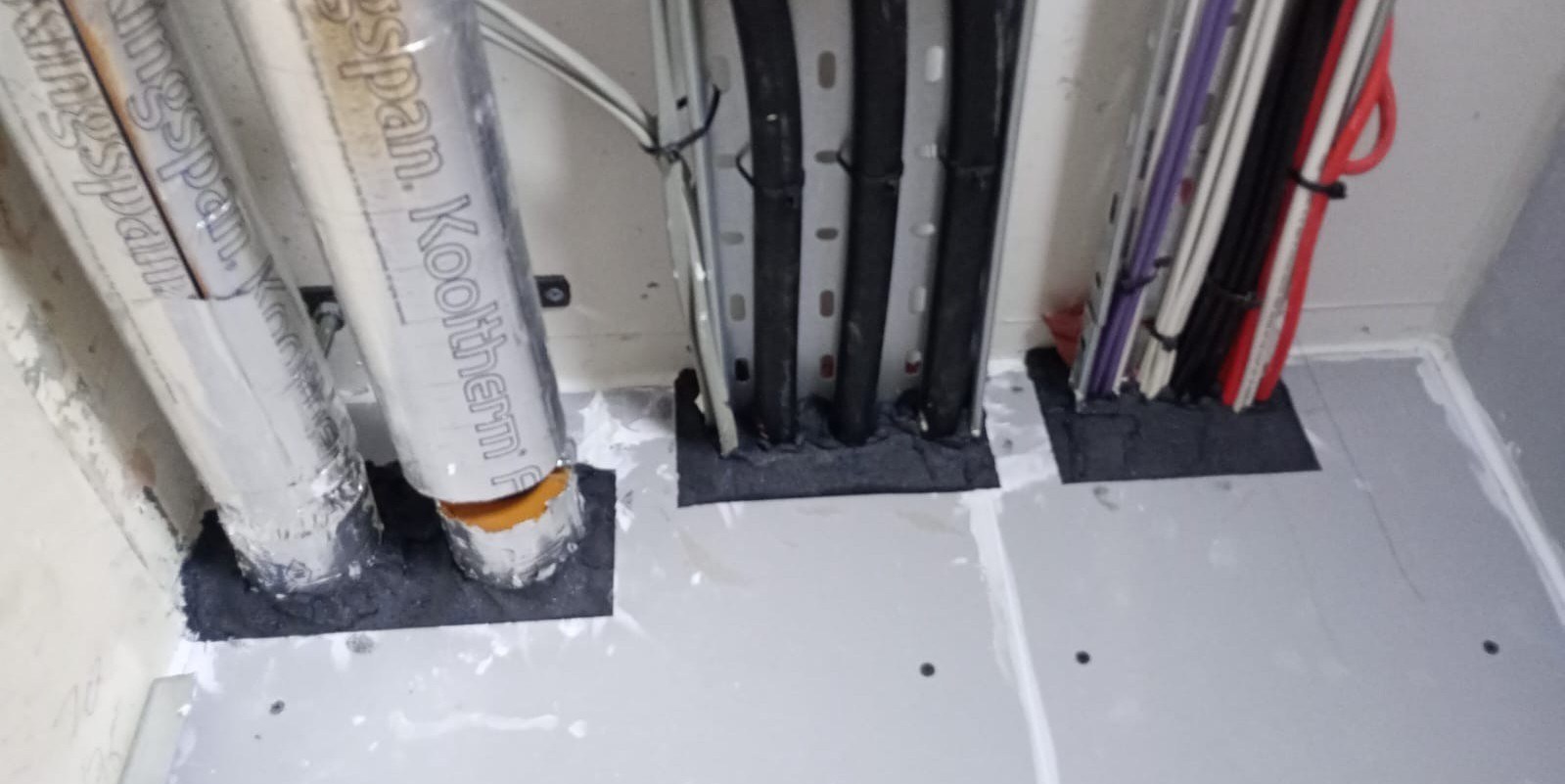 Fire-stopping around pipes and cables passing through a floor in a service riser